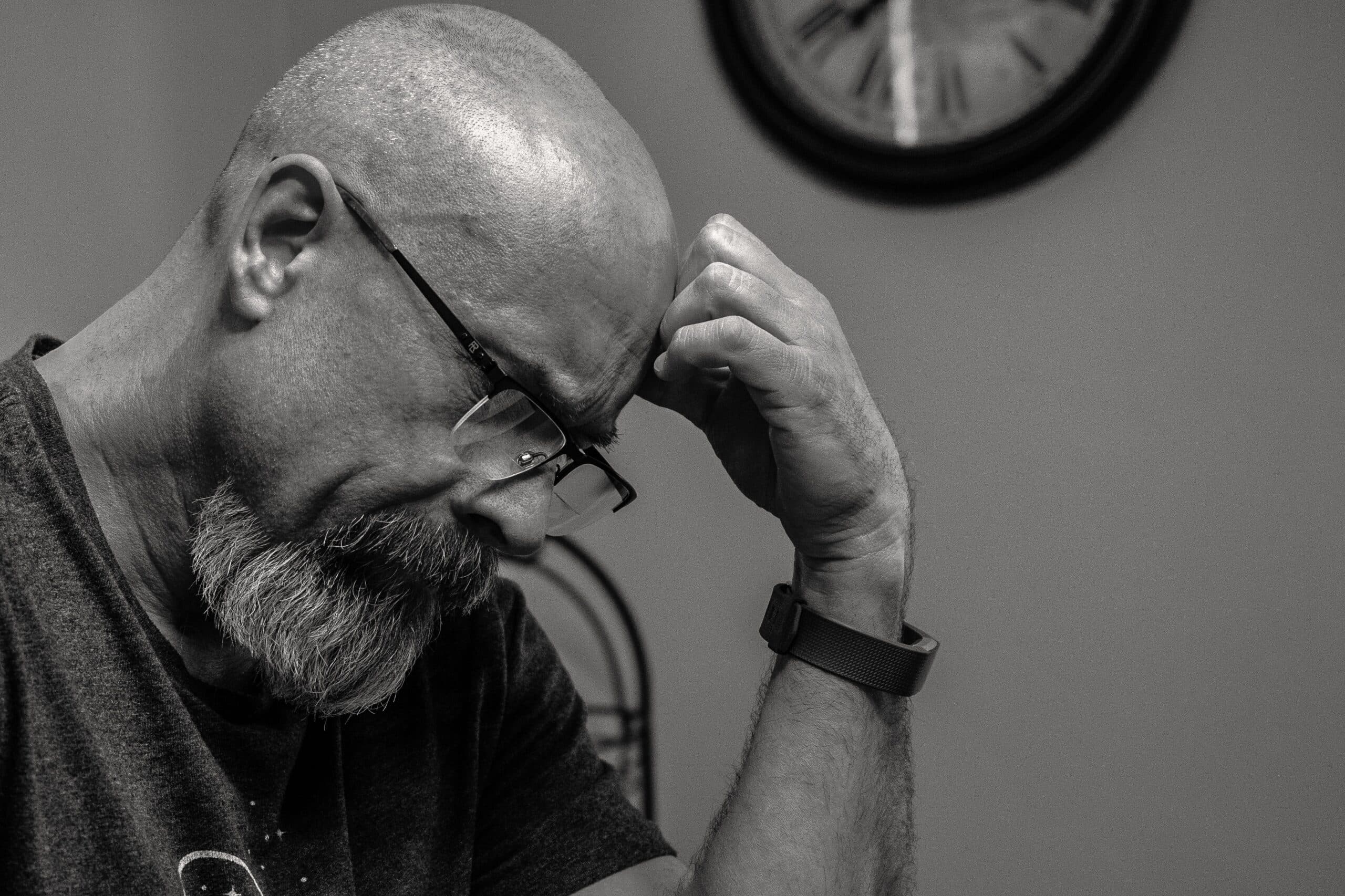 Black and white image of a bald man in deep thought