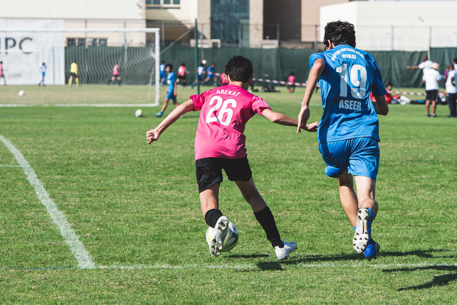 Two youth soccer players chasing the ball on a field