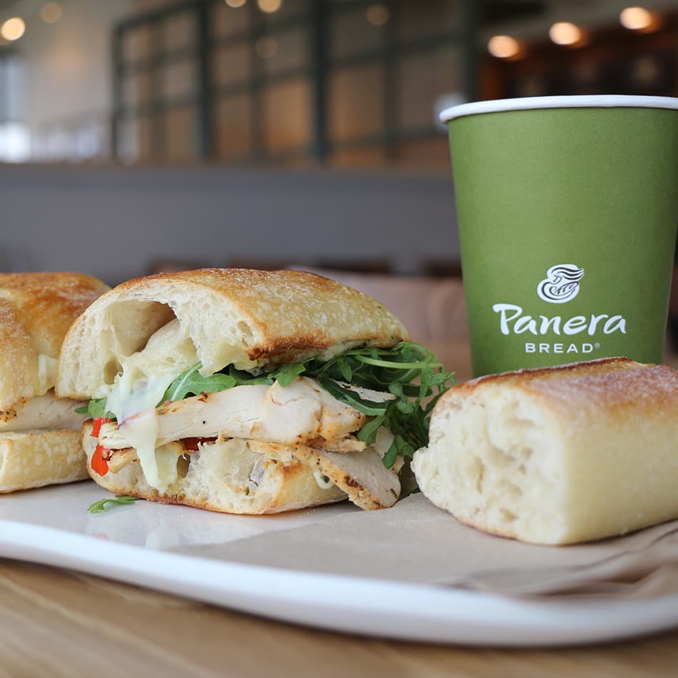 Panera Bread sandwich and coffee cup on a café table