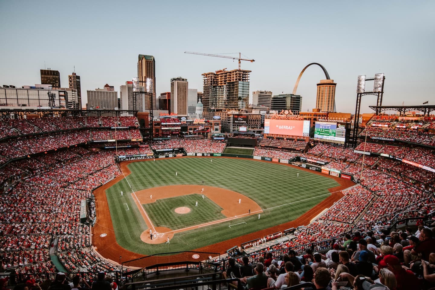 Busch Stadium in St Louis filled with fans with the Gateway Arch in the background