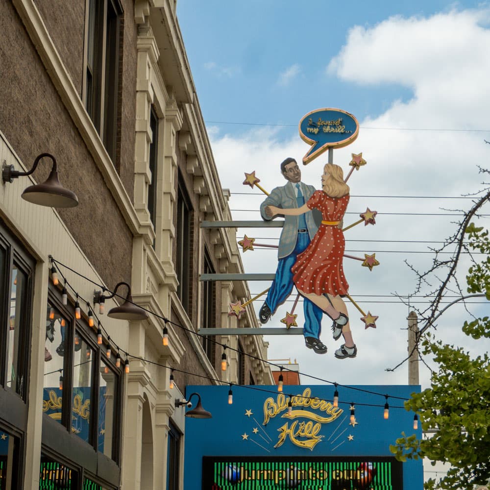 Neon sign of a dancing couple above a Delmar Loop storefront